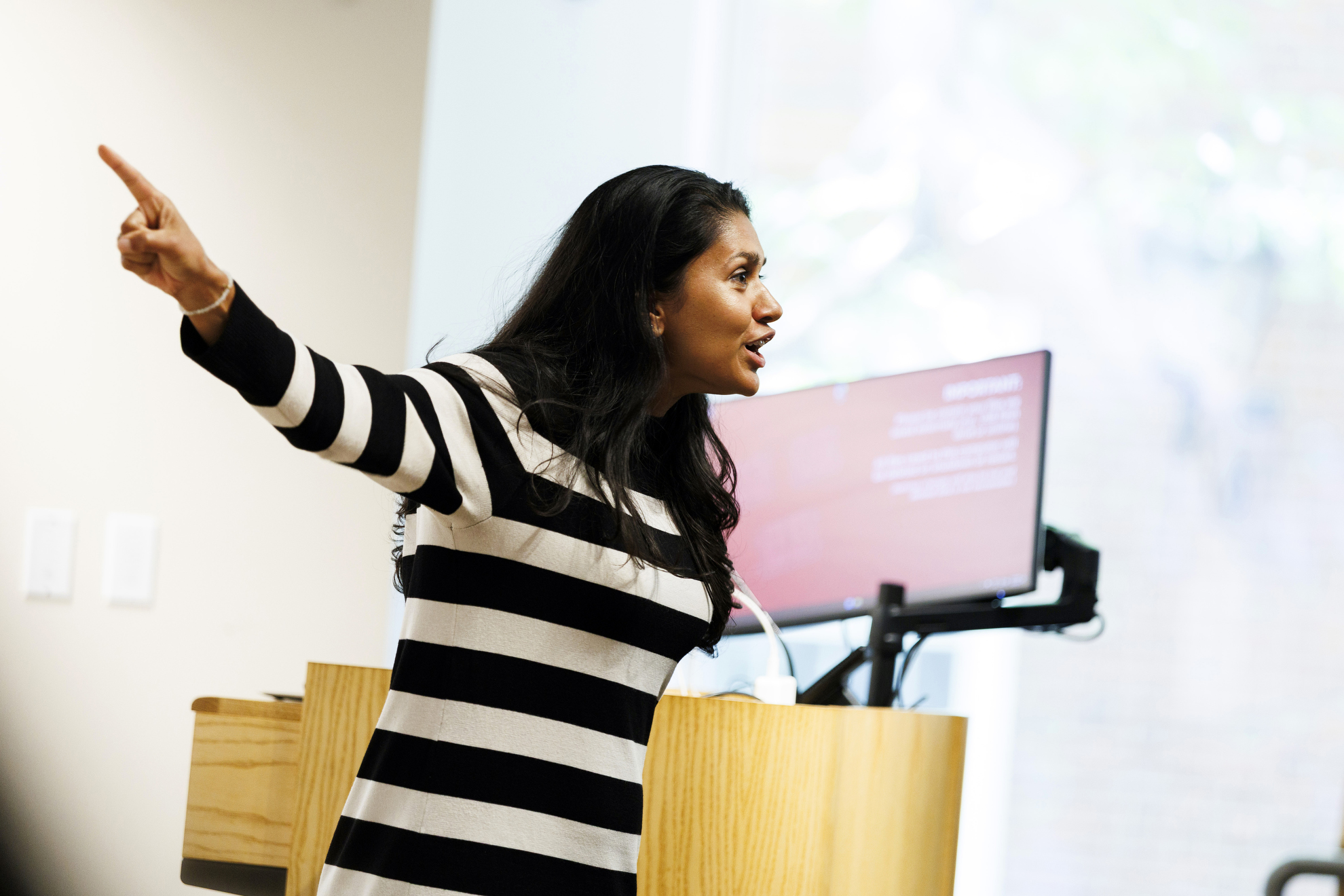 Tara Menon is pictured at the podium giving introductory remarks imploring students to “do the readings.”